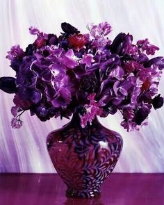 a purple vase filled with lots of purple flowers