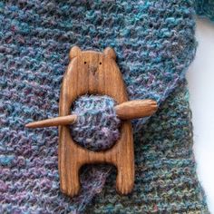 a wooden bear with a ball of yarn in it's mouth on top of a knitted blanket