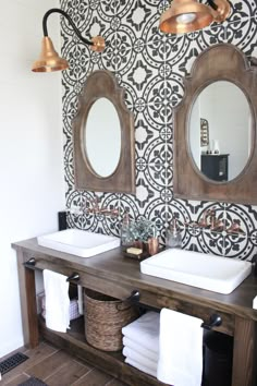 two bathroom sinks with mirrors above them in front of a wallpapered wall and black and white tiles