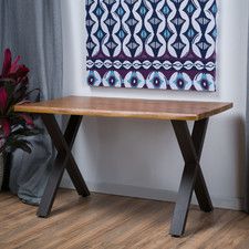 a wooden table sitting in front of a window with curtains on the windowsill and a painting hanging above it