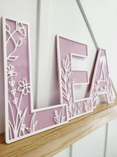 a pink and white wooden sign that says love with flowers in the letters on it