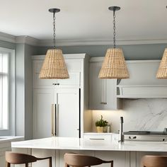 three lamps hanging over a kitchen island with stools in front of the counter top