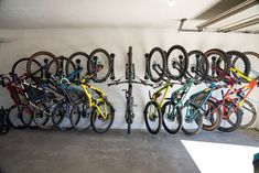 a bunch of bikes that are hanging on the side of a wall in a garage