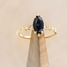 a ring with a large blue stone on it sitting on top of a piece of wood