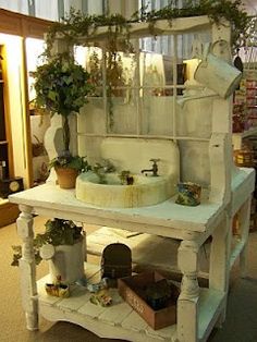 an old fashioned sink with potted plants on the top and shelves below it in a store