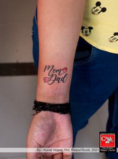 a woman's wrist tattoo with the words mom and dad written on her arm