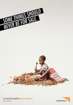 a young boy sitting on top of a pile of rubble next to a sign that says, some things should never be for sale