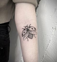 a ladybug tattoo on the left inner arm and lower arm, with two ladybugs attached to it