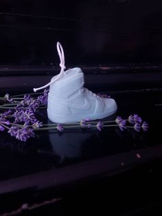 a pair of white sneakers sitting on top of a table next to purple flowers and lavender