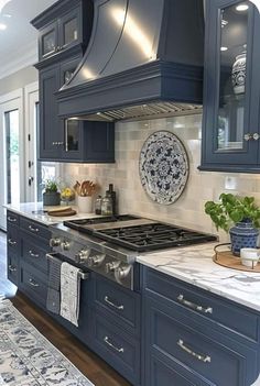 a kitchen with blue cabinets and marble counter tops, an oven hood over the stove