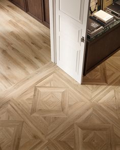 an open door leading to a kitchen with wooden floors and cabinets in it's center