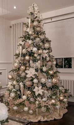 a decorated christmas tree in a living room with white and silver ornaments on the top