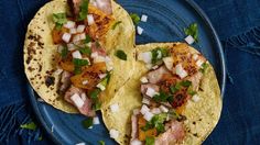 two tacos on a blue plate with onions and cilantro