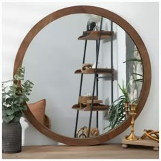 a round mirror sitting on top of a wooden table next to a potted plant