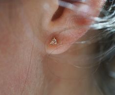 a close up of a person's ear with two small diamond studs