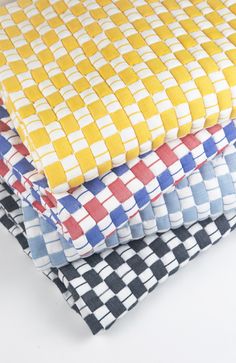 three different colored checkered cloths stacked on top of each other, one yellow and the other blue