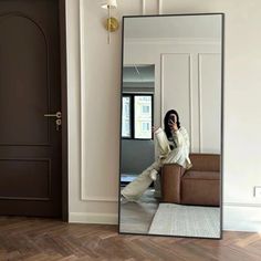 a woman sitting on a couch in front of a mirror