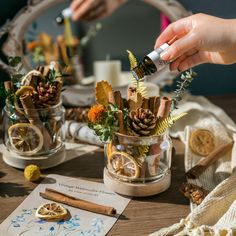 a person is decorating a glass vase with pine cones and other things in it