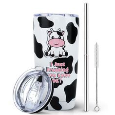 a cup with a straw in it and a cow design on the side next to it