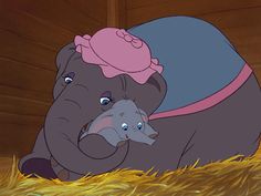 an elephant with a pink hat on it's head next to a baby elephant