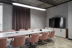 an empty conference room with pink chairs and a flat screen tv