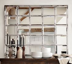 a large mirror sitting on top of a wooden dresser next to a table filled with dishes