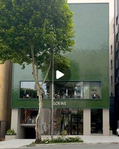 the corner of a building with a tree in front of it and a car parked on the street