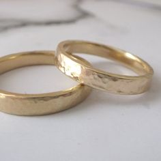 two gold wedding rings sitting next to each other