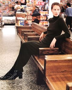 a woman sitting on top of a wooden bench