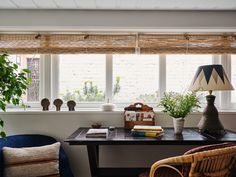 a room with two chairs and a table in front of a window filled with plants