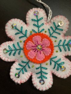 a snowflake ornament is hanging on a black surface with some beads