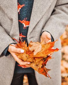 a woman holding leaves in her hands and wearing a tie with deer designs on it