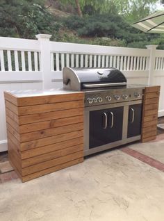 an outdoor kitchen with grill and umbrella