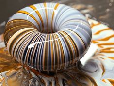 a decorative glass object sitting on top of a white and orange plate with swirl designs