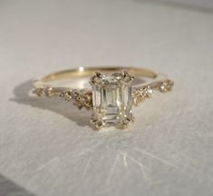 an engagement ring with a large emerald stone surrounded by small white and yellow diamond accents