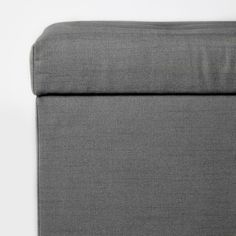 the back end of a gray couch on a white surface with no one in it