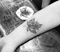 a black and white photo of a person's arm with a leaf tattoo on it