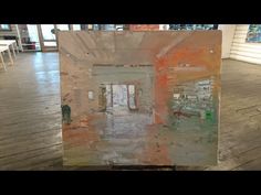 an abstract painting is displayed on a wooden floor in the middle of a room filled with chairs and tables