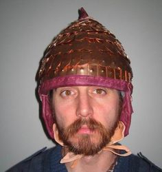 a man with a beard wearing a brown and pink hat on top of his head