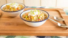 two bowls filled with food sitting on top of a wooden cutting board