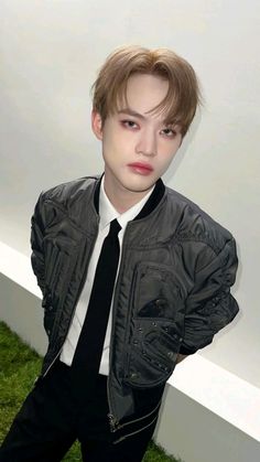 a young man in a black tie and jacket posing for the camera with his hands on his hips