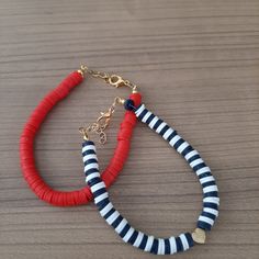 two bracelets with red, white and blue beads on a wooden table next to each other