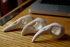 three small white sculptures sitting on top of a wooden table next to a laptop computer