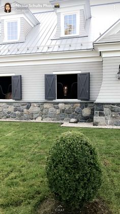 two dogs are looking out the windows of a white house with black shutters on it