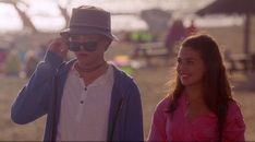 a man standing next to a woman on top of a beach