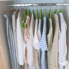 an organized closet with clothes hanging on hooks and green clips to hang them from the ceiling