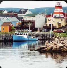 a blue and white boat sitting in the water next to some houses with red lighthouses on top