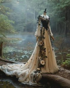 a dress made out of fabric and flowers in the middle of a forest with water