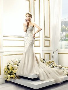 a woman in a wedding dress standing on a platform with flowers around her and talking on the phone