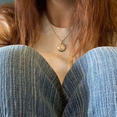 a woman with red hair is wearing a blue shirt and has a necklace on her neck